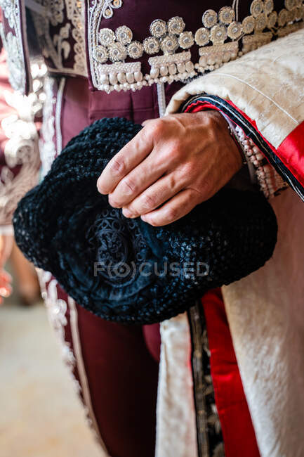 Colheita toureiro irreconhecível em traje vermelho tradicional e com chapéu montera se preparando para corrida — Fotografia de Stock