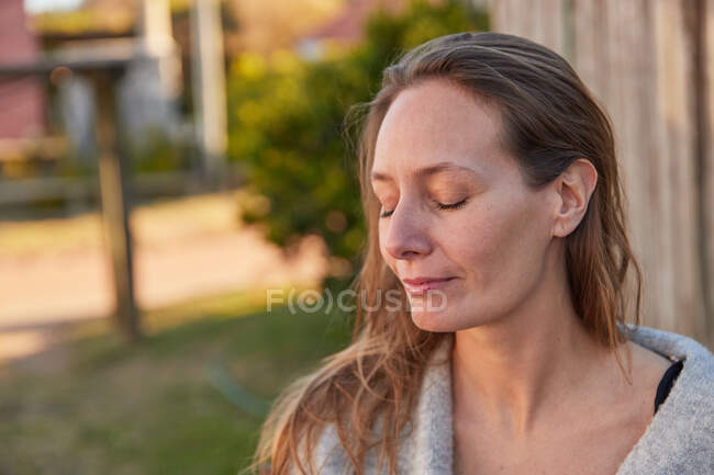 Mulher macia com olhos fechados em pé no exuberante jardim de verão e desfrutando de fim de semana — Fotografia de Stock