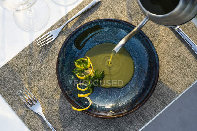 Garçom derramando sopa de lentilha no restaurante de alta cozinha ao ar livre — Fotografia de Stock