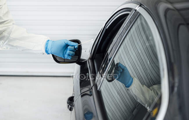 Biologe mit Schutzhandschuhen bei der Durchführung eines Coronavirus-Tests an einer Person im Auto — Stockfoto