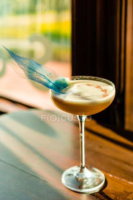 Творческая фантазия ярко-желтый алкогольный напиток подается в коктейльном бокале на деревянном барной стойке — стоковое фото