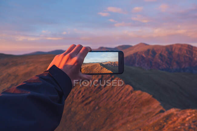 Anonyme männliche Wanderer fotografieren das Hochland bei Sonnenuntergang in Wales mit dem Smartphone — Stockfoto