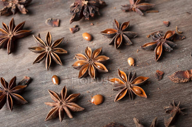 Closeup of aromatic dried anise stars with seeds scattered on rustic wooden table for gastronomy concept background — Stock Photo