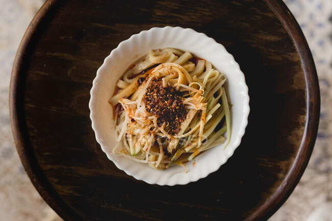 D'en haut ramen frais chinois avec des épices dans une assiette en porcelaine blanche placée sur un plateau en bois — Photo de stock