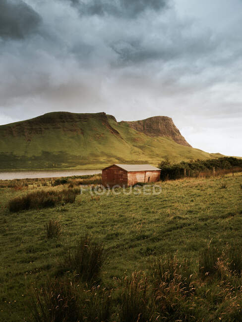 Picturesque view of a cabin building in middle of green valley by high mountain range in United kingdom — Stock Photo