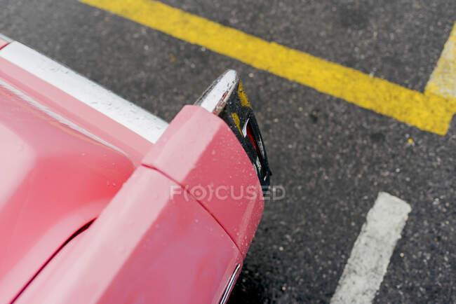 Desde arriba detalle de enfoque trasero de un coche clásico de color rosa en el suelo de asfalto - foto de stock