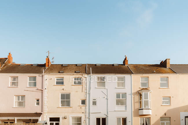 Casas tradicionales con techos de baldosas situadas contra el cielo azul sin nubes en la calle de la ciudad en el Reino Unido - foto de stock