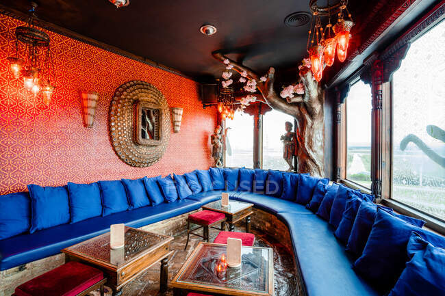 Acogedor interior de bar de cócteles con cómodo sofá con cojines y mesas durante el día - foto de stock