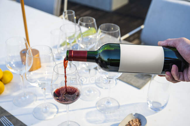 Garçom derramando vinho tinto em um copo no restaurante de alta cozinha ao ar livre — Fotografia de Stock