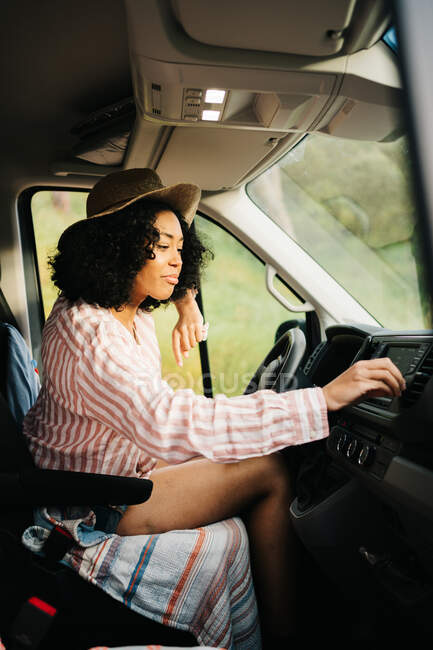 Літнім днем припарковувалась молода афроамериканська жінка - водій, яка налаштовує радіо у фургоні. — стокове фото