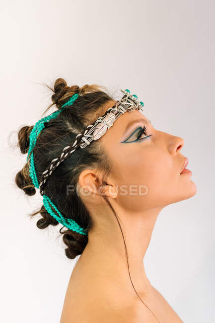 Vista laterale di bella giovane modello femminile con trucco stile orientale ed elegante ornamento d'argento con pietre verdi sulla testa — Foto stock