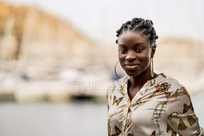 Стеблива задумлива афроамериканська леді з африканськими браїдами серйозно дивиться на камеру в парку. — стокове фото