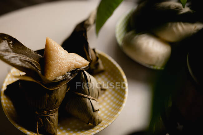 Albóndigas de arroz de hoja de bambú abiertas y cubiertas colocadas en una placa comprobada linda - foto de stock