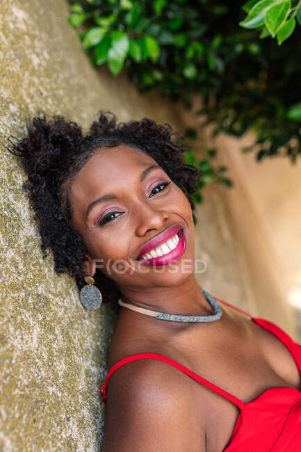 Confident African American female standing and looking at camera near stone wall — Stock Photo
