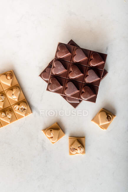 Vue du dessus de délicieux bonbons au chocolat avec des noix en forme de cœur éparpillés sur fond blanc — Photo de stock