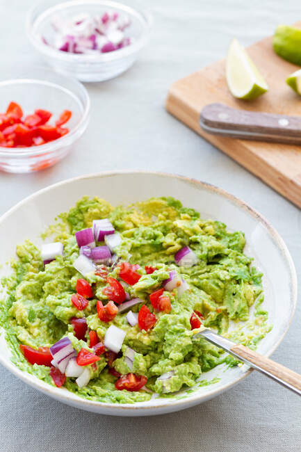 From above of tasty guacamole with fresh red onion slices in ceramic bowl on table — Stock Photo