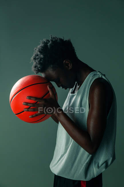 Black woman with basketball outfit in the studio using color gels and projector lights over blue background — Stock Photo