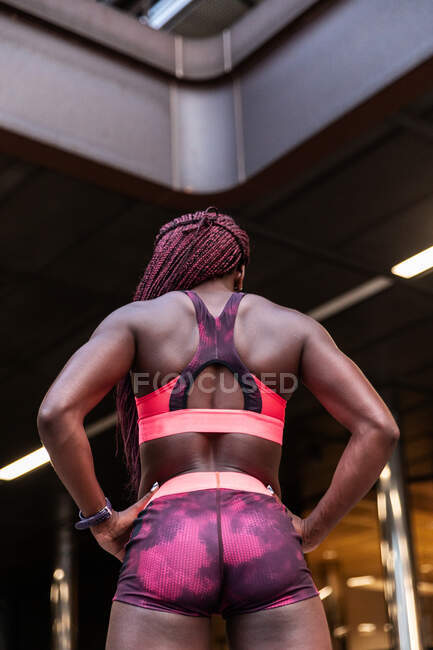 Back view of ethnic sporty muscular woman with braids standing on street — Stock Photo