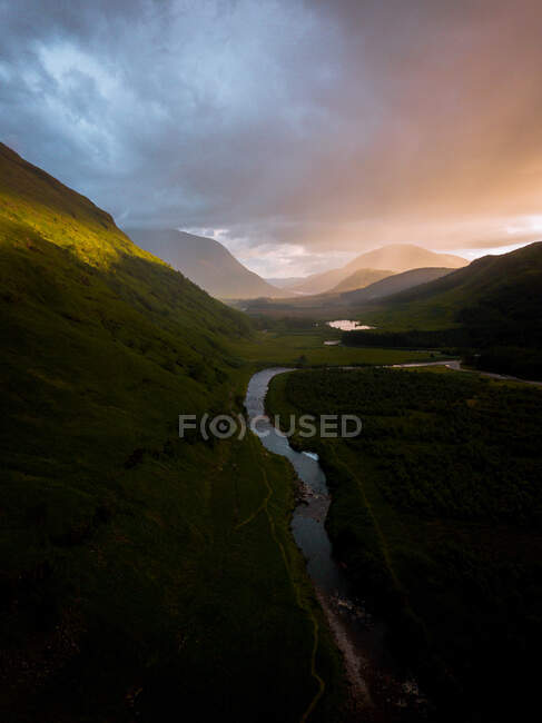 Overcast sundown sky over hill slope and curvy river in peaceful evening in Glen Etive, United Kingdom — Stock Photo