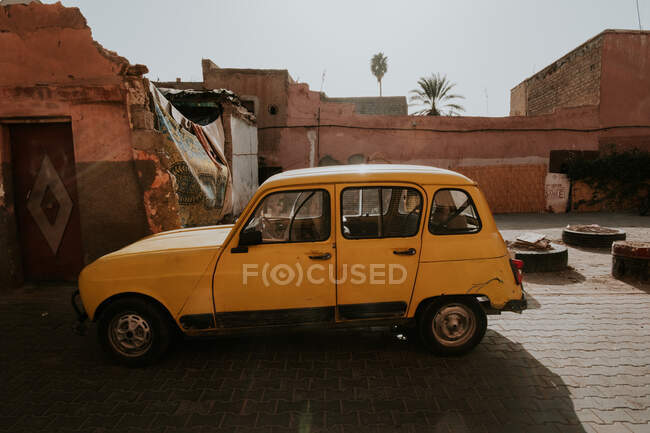 Voiture ancienne garée près de maisons détruites dans la rue du ghetto à Marrakech, Maroc — Photo de stock