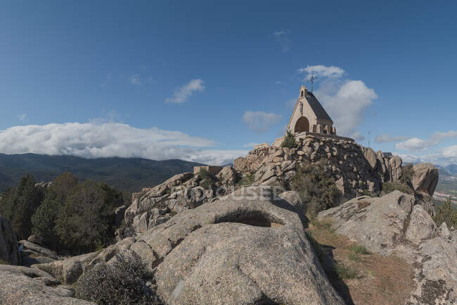Fish eye view of rough stony mountains and small church building against cloudy blue sky in Sierra de Guadarrama National Park in Madrid, Spain — Stock Photo
