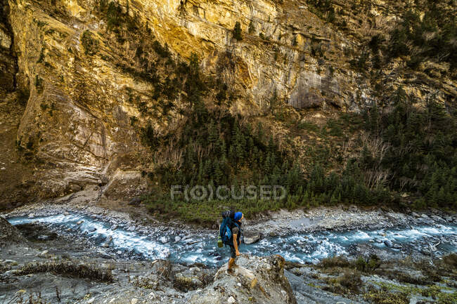 High angle side view of anonymous backpacker standing on rock and admiring view of fast river in Himalayas in Nepal — Stock Photo