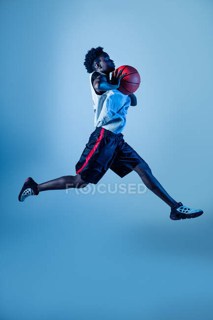 Femme noire avec tenue de basket-ball en studio à l'aide de gels de couleur et de projecteurs — Photo de stock