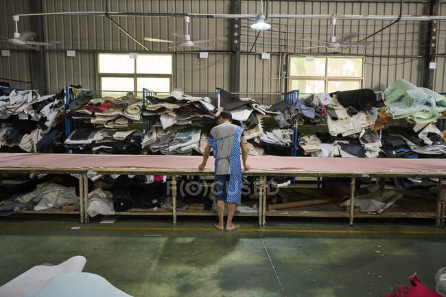 Worker in storage room for different materials used for making shoes at Chinese shoes factory — Stock Photo