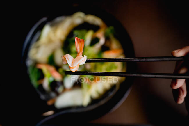 Top view of bowl of tasty oriental noodle soup with fresh prawns placed on table against black background — Stock Photo