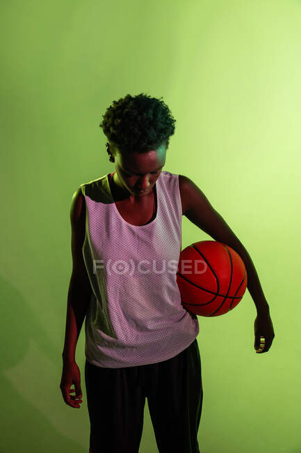 Mujer negra con traje de baloncesto en el estudio usando geles de color y luces de proyector - foto de stock