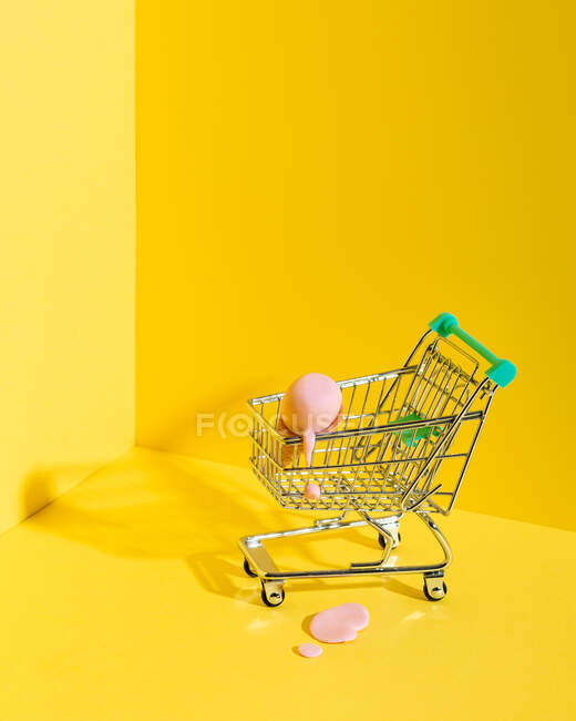 Сверху композиция миниатюрной тележки с разнообразными разноцветными конусами мороженого, расположенной рядом с упавшим голубым мороженым на желтом фоне — стоковое фото