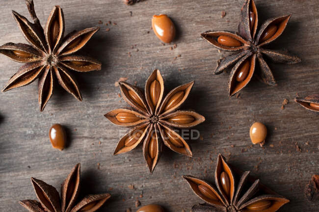 Closeup de estrelas de anis secas aromáticas com sementes espalhadas na mesa de madeira rústica para fundo conceito de gastronomia — Fotografia de Stock