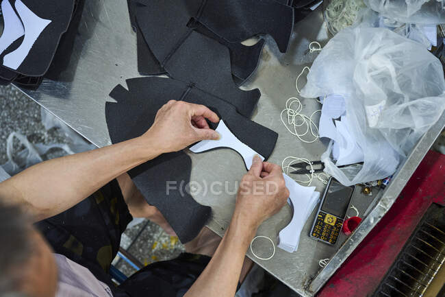 Détail du travailleur de la main assemblant des pièces de tissu sur l'usine de chaussures chinoises — Photo de stock