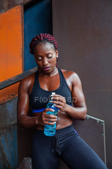 Donna etnica atletica che beve acqua — Foto stock