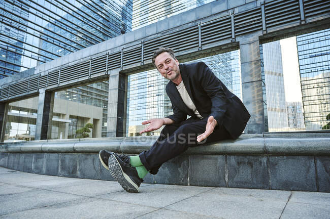 Дизайнер, сидящий снаружи здания офиса, отдыхающий и улыбающийся — стоковое фото