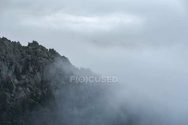 Paisagem calma com cordilheira coberta de nevoeiro contra céu nebuloso matutino no Parque Nacional de Guadarrama, em Madri, Espanha — Fotografia de Stock