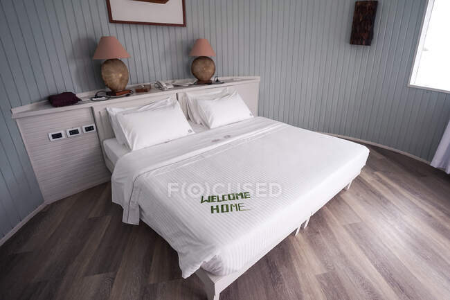Malediven Hotelzimmer mit Bett in weißen Laken mit Buchstaben aus Bambusblättern geschrieben Willkommensgruß zu Hause — Stockfoto