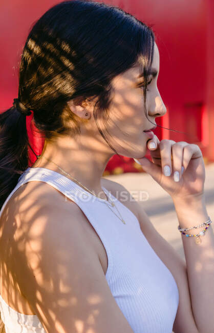 Vue latérale de jeune adolescent féminin coûteux avec queue de cheval dans le bracelet regardant loin le jour ensoleillé — Photo de stock