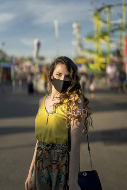 Mulher encantada em máscara protetora durante coronavírus olhando para a câmera enquanto passa o fim de semana no recinto de feiras — Fotografia de Stock