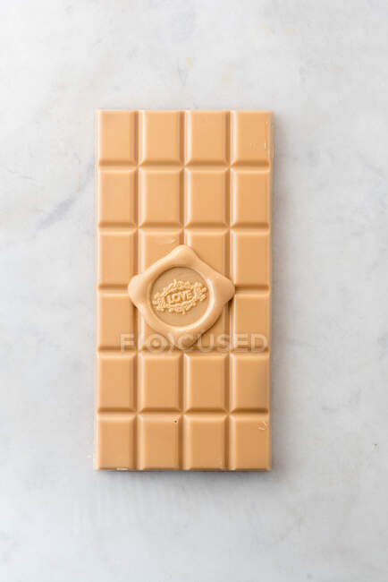 Vista superior de deliciosa barra de caramelo con amor escrito de corazón sobre fondo de mesa de mármol - foto de stock