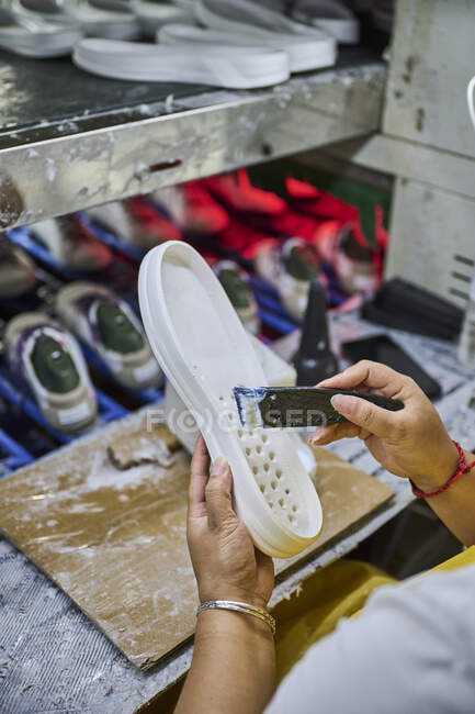 Détail du travailleur appliquant de la colle sur la semelle des chaussures dans une ligne de production d'usine de chaussures chinoises — Photo de stock