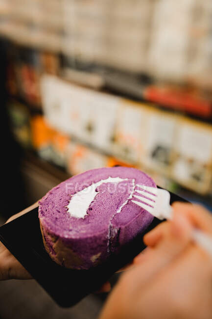 Hände stehen mit gebackenen appetitlichen Süßkartoffelrolle auf Teller mit Einweg-Plastikgabel im Café — Stockfoto