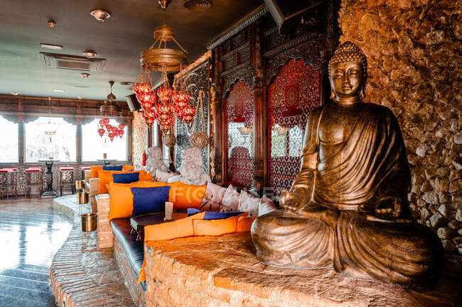 Interior de bar de coquetéis com estátua de Buda e sofás acolhedores projetados em estilo oriental — Fotografia de Stock