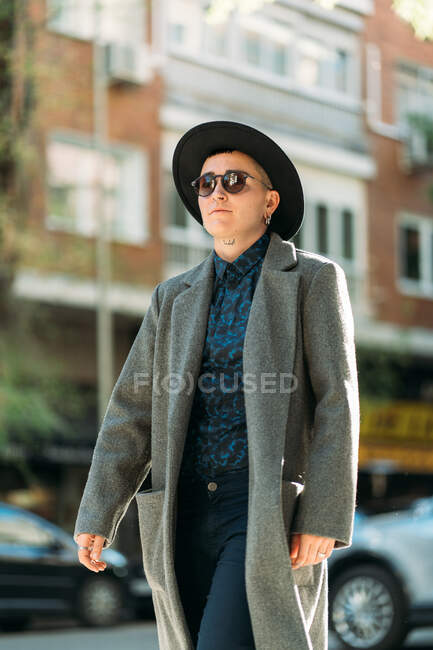 Young transgender person in classy coat and hat looking away in daylight — Stock Photo