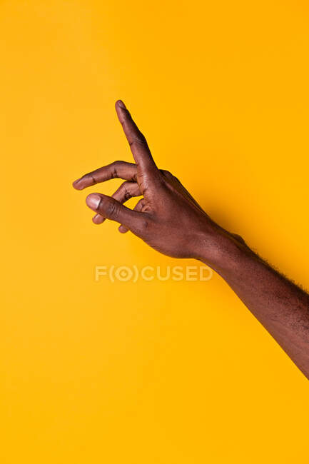 Обрезание предплечья и руки афро-американского человека, поднимающего указательный палец на жёлтый фон — стоковое фото