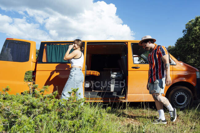 Encantada pareja de viajeros de pie en furgoneta y durante la aventura de verano - foto de stock