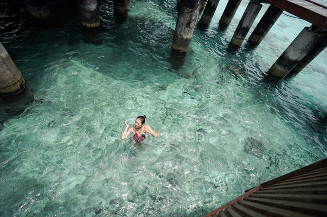 Над этнической азиаткой в купальнике расслабляет купание в бирюзовом Мальдивском океане — стоковое фото