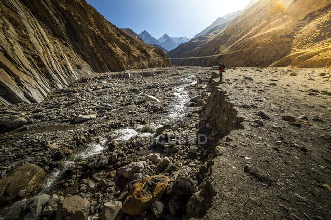 Неузнаваемый путешественник, стоящий на холме и наслаждающийся пейзажем реки, текущей в горах Гималаев в Непале — стоковое фото