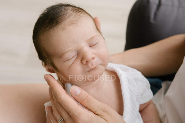 Dall'alto di madre irriconoscibile seduta con adorabile bambino addormentato sul pavimento a casa — Foto stock