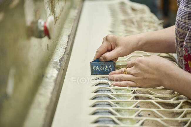 Detalle del trabajador que usa el patrón de corte mientras corta la tela en la fábrica de zapatos chinos - foto de stock